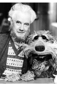 Black and white phot of a bearded man and his dog. Man is human, dog is a puppet.