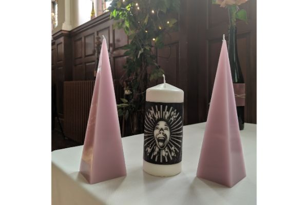 Two taller pink candles either side of a central candle on a table